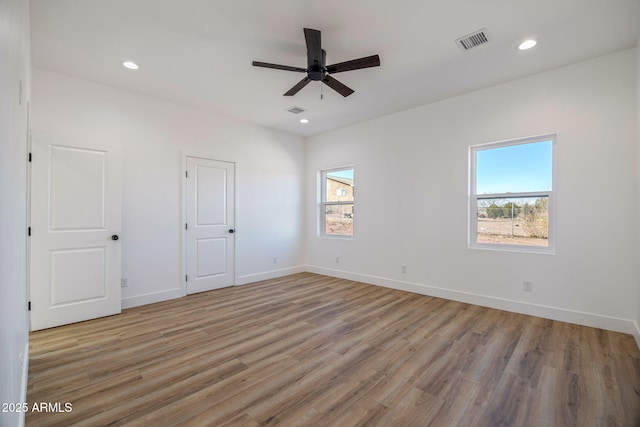 empty room with ceiling fan, a healthy amount of sunlight, and light wood-type flooring