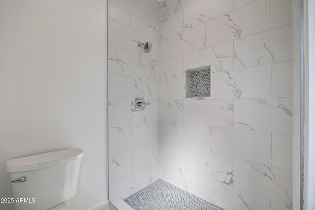 bathroom with a tile shower and toilet