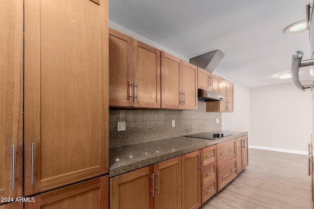 kitchen featuring decorative backsplash, black electric stovetop, and light hardwood / wood-style flooring