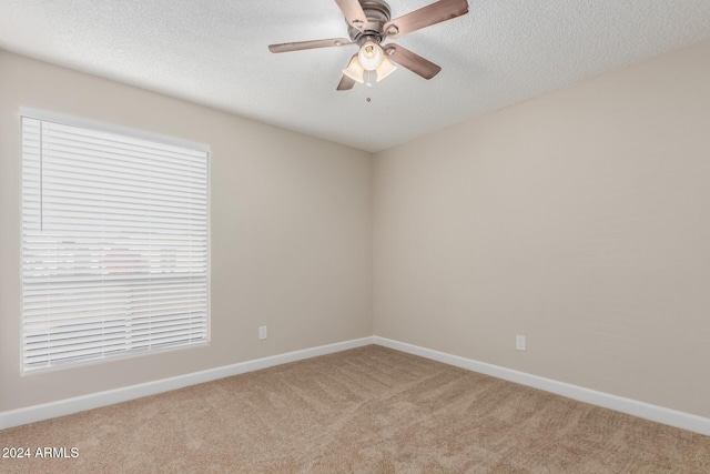 carpeted empty room with ceiling fan and a textured ceiling