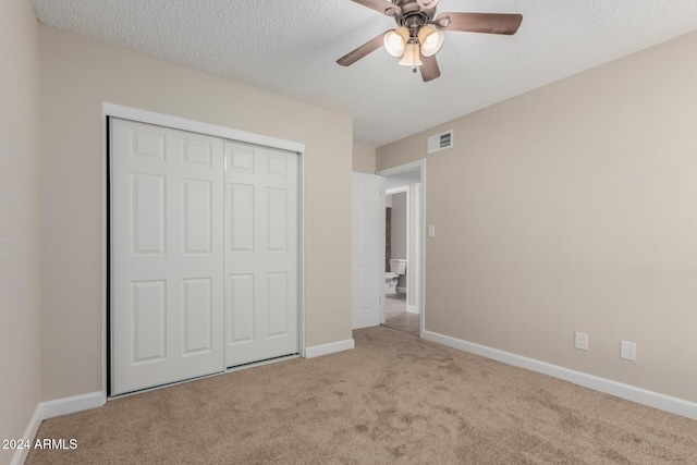 unfurnished bedroom featuring a textured ceiling, light colored carpet, a closet, and ceiling fan