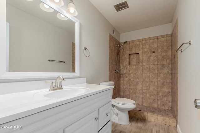 bathroom featuring vanity, toilet, wood-type flooring, and tiled shower