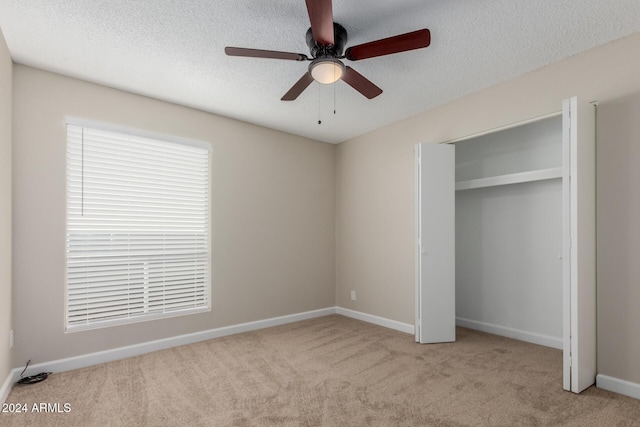 unfurnished bedroom with light carpet, a textured ceiling, a closet, and ceiling fan