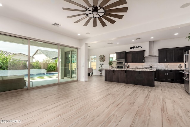 2316 E Canary Dr, Gilbert, AZ 85297 - kitchen with wall chimney exhaust hood, ceiling fan, light wood-style floors, a center island with sink, and recessed lighting