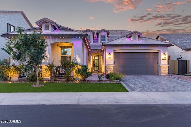 2316 E Canary Dr, Gilbert, AZ 85297 - mediterranean / spanish-style house featuring decorative driveway, an attached garage, brick siding, stucco siding, and a front lawn