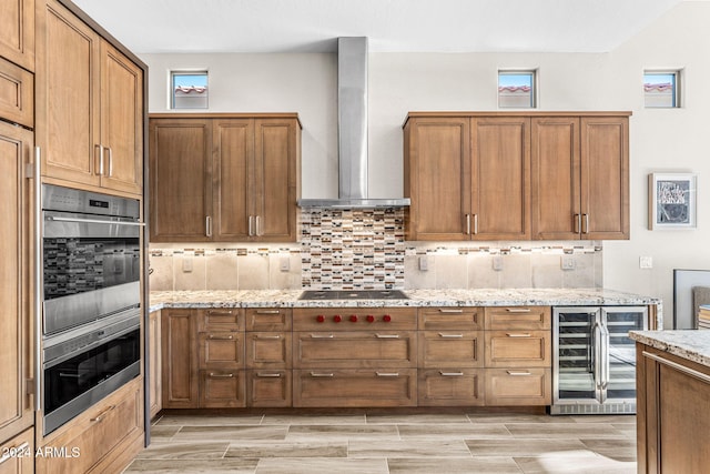 kitchen with backsplash, black electric stovetop, wine cooler, wall chimney exhaust hood, and light stone counters