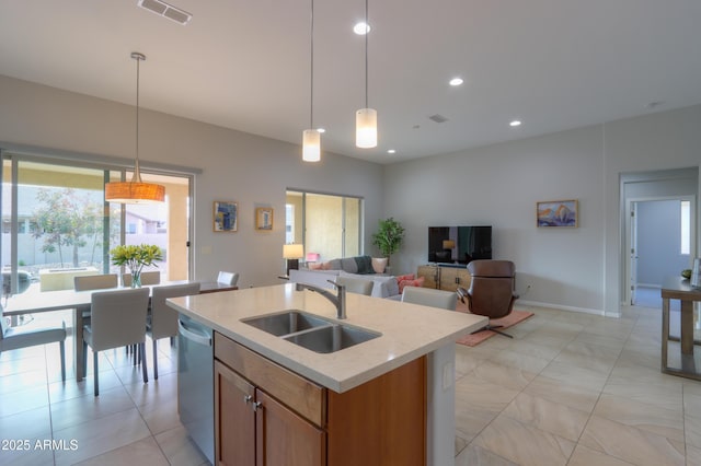 kitchen featuring decorative light fixtures, sink, stainless steel dishwasher, and an island with sink