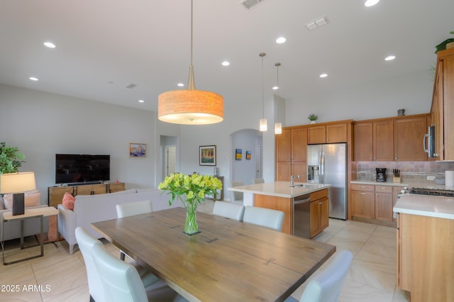 dining space featuring a high ceiling, sink, and light tile patterned flooring