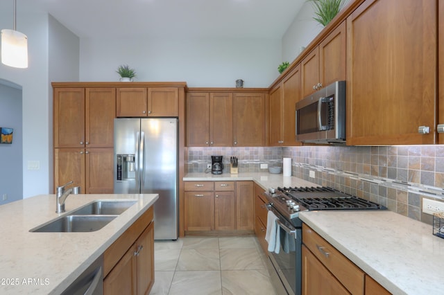 kitchen featuring light stone countertops, appliances with stainless steel finishes, tasteful backsplash, sink, and hanging light fixtures