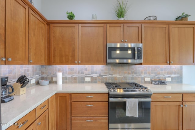 kitchen featuring appliances with stainless steel finishes, backsplash, and light stone countertops