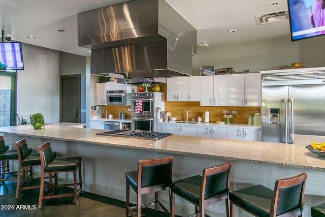 kitchen featuring sink, kitchen peninsula, appliances with stainless steel finishes, a kitchen breakfast bar, and white cabinets