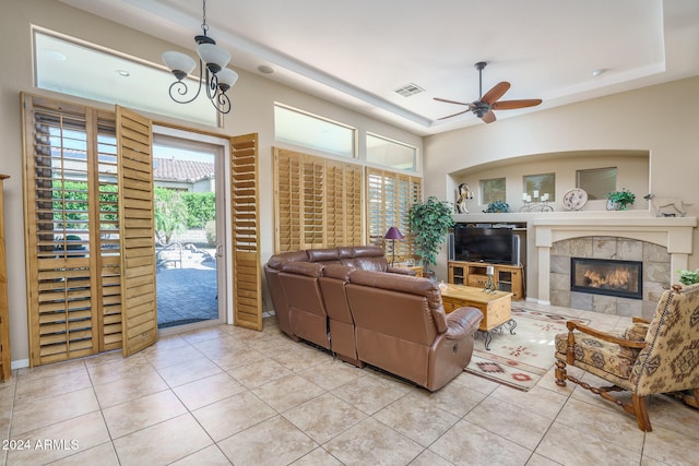 living room with ceiling fan with notable chandelier, light tile patterned floors, and a fireplace