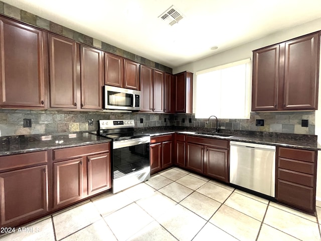 kitchen with backsplash, sink, light tile patterned flooring, and stainless steel appliances