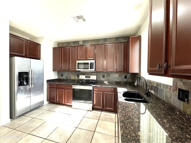 kitchen featuring appliances with stainless steel finishes, dark stone counters, sink, and backsplash