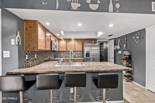 6408 W College Dr, Phoenix, AZ 85033 - kitchen featuring sink, backsplash, a kitchen bar, light tile patterned floors, and stainless steel appliances