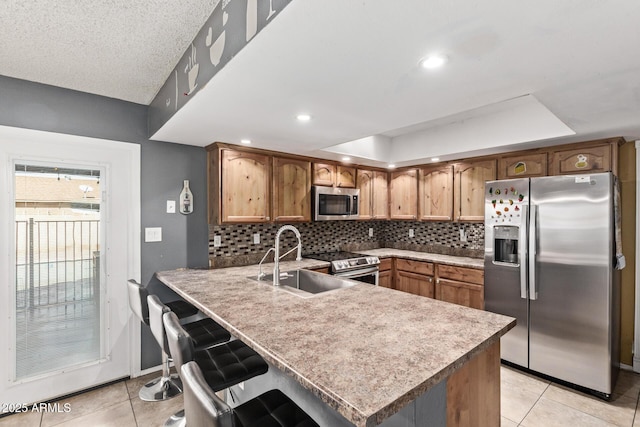 6408 W College Dr, Phoenix, AZ 85033 - kitchen with sink, appliances with stainless steel finishes, a kitchen breakfast bar, tasteful backsplash, and kitchen peninsula