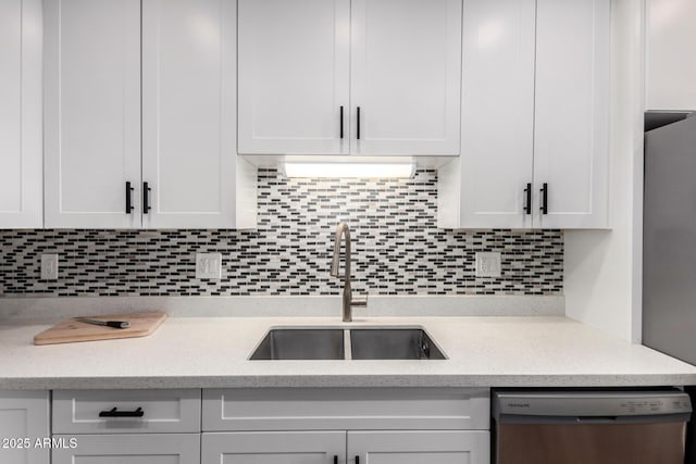 kitchen featuring light stone counters, a sink, white cabinetry, decorative backsplash, and dishwasher