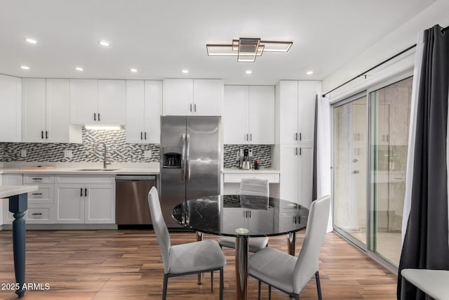 kitchen with stainless steel appliances, wood finished floors, a sink, and white cabinets