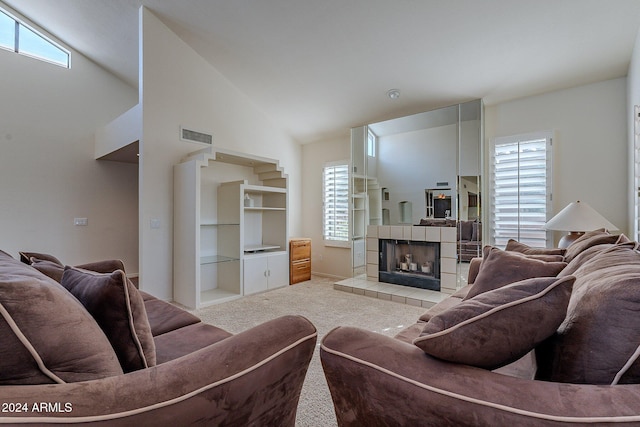 carpeted living room featuring a tile fireplace, high vaulted ceiling, and a healthy amount of sunlight