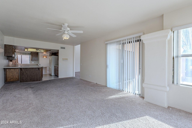 unfurnished living room featuring light carpet and ceiling fan