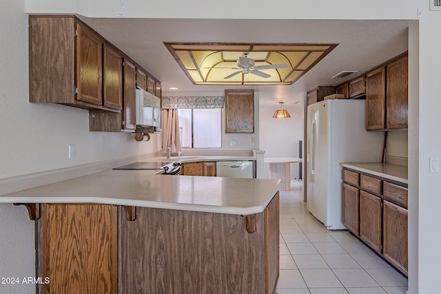 kitchen with kitchen peninsula, white appliances, a breakfast bar, and hanging light fixtures