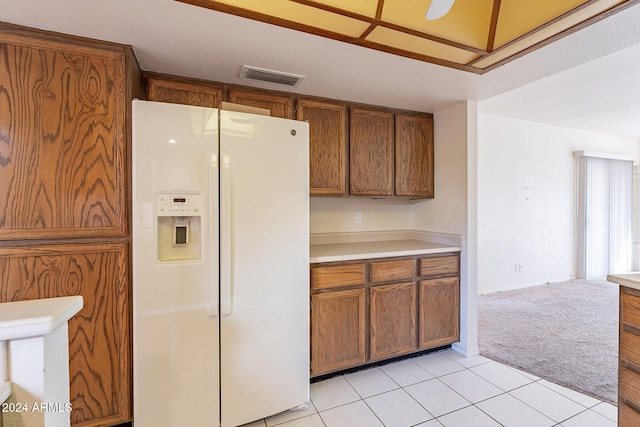 kitchen with a textured ceiling, light tile patterned floors, and white refrigerator with ice dispenser