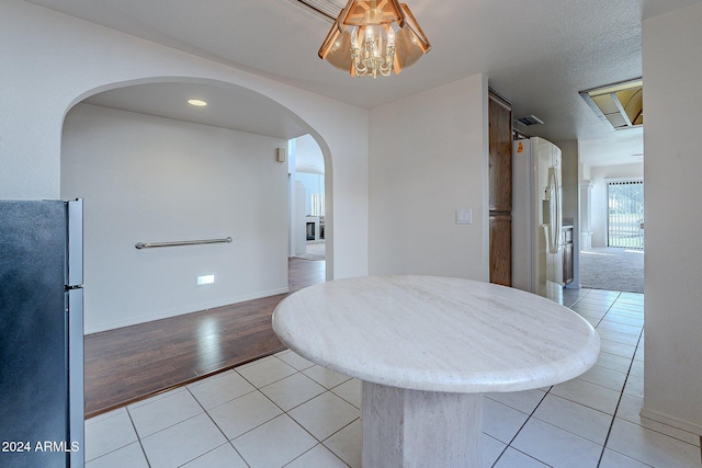 unfurnished dining area featuring a textured ceiling and light hardwood / wood-style flooring