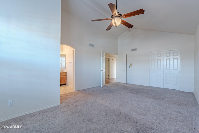 unfurnished bedroom with light carpet, high vaulted ceiling, ensuite bath, ceiling fan, and a closet