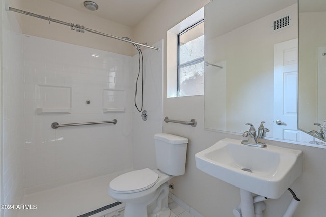 bathroom featuring tiled shower, toilet, and sink