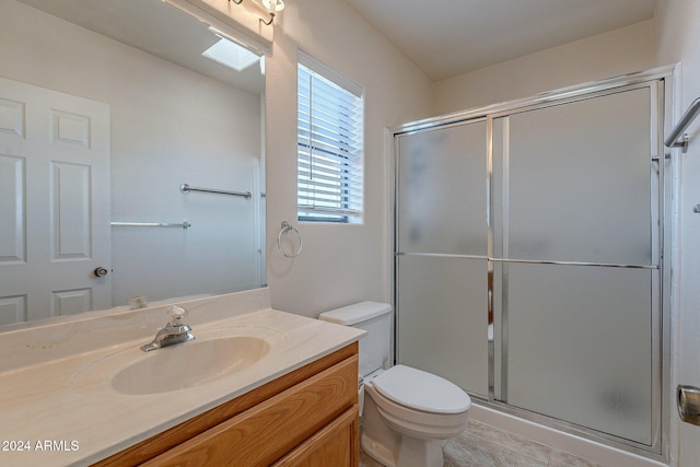 bathroom with tile patterned flooring, a shower with door, vanity, and toilet