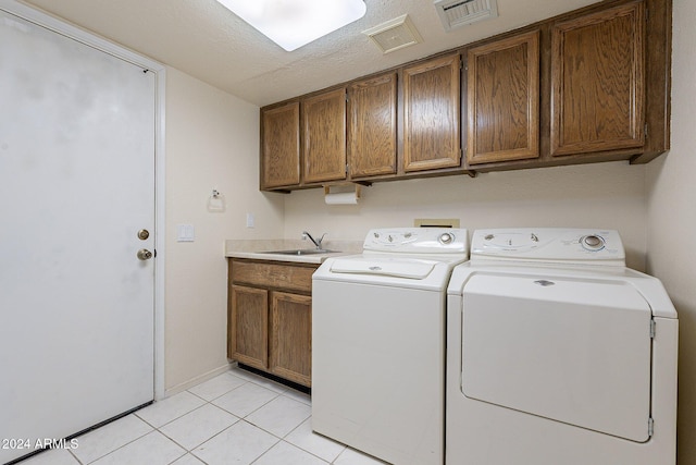 washroom with cabinets, sink, washer and dryer, a textured ceiling, and light tile patterned flooring