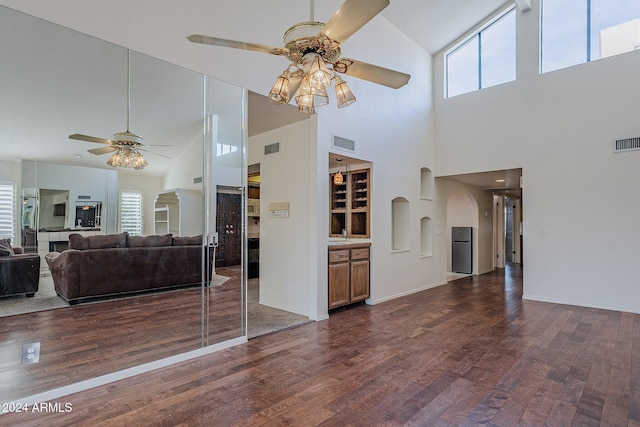 unfurnished living room with dark hardwood / wood-style floors, ceiling fan, and high vaulted ceiling