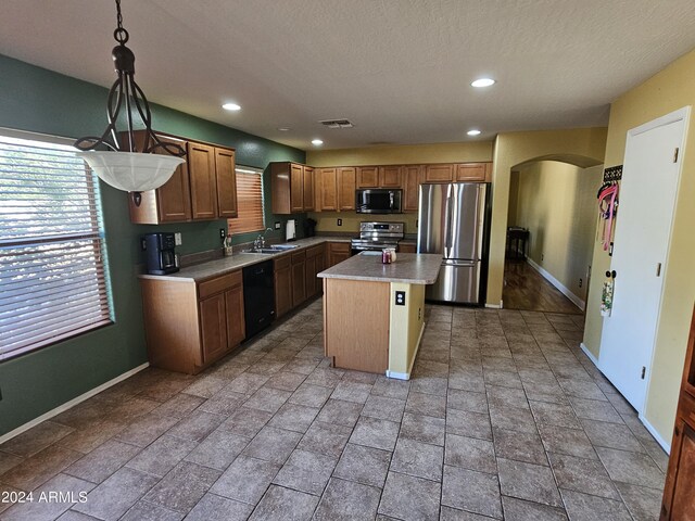 kitchen featuring black appliances, sink, a kitchen island, a textured ceiling, and pendant lighting