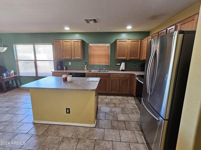 kitchen featuring appliances with stainless steel finishes, a textured ceiling, sink, and a kitchen island