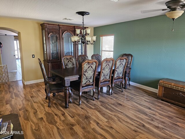 dining room with a textured ceiling, ceiling fan with notable chandelier, and dark hardwood / wood-style flooring