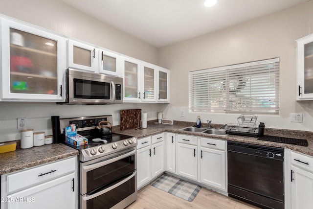 kitchen featuring white cabinetry, sink, light hardwood / wood-style flooring, and appliances with stainless steel finishes