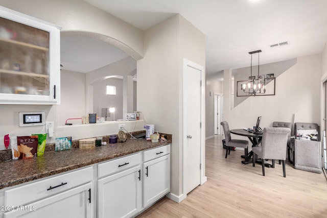 kitchen with white cabinetry, dark stone countertops, light hardwood / wood-style flooring, and pendant lighting