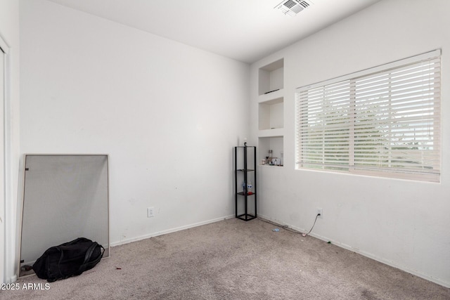 carpeted empty room with built in shelves