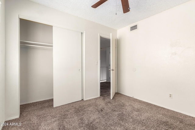 unfurnished bedroom featuring a textured ceiling, a closet, carpet flooring, and visible vents