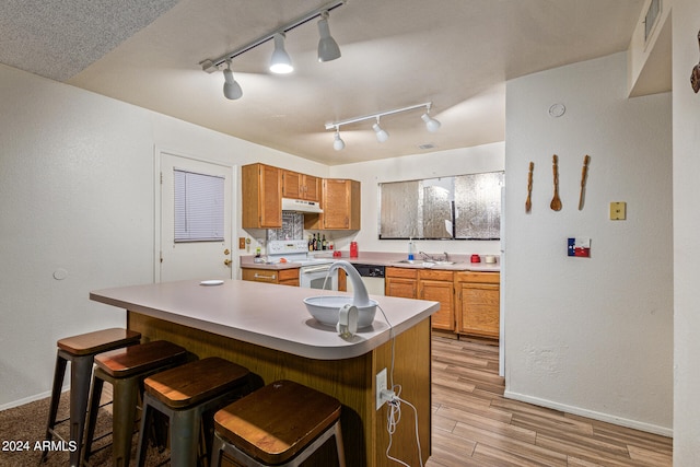 kitchen with a kitchen bar, white electric stove, rail lighting, light wood-type flooring, and a textured ceiling