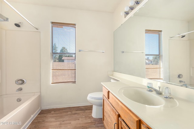 bathroom with bathing tub / shower combination, toilet, vanity, wood finished floors, and baseboards