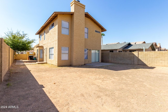 back of property with a chimney, a fenced backyard, and stucco siding