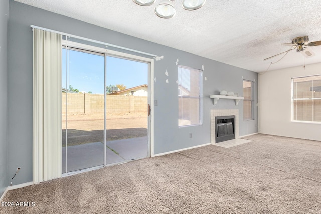 unfurnished living room featuring carpet floors, a fireplace, a textured ceiling, and a ceiling fan