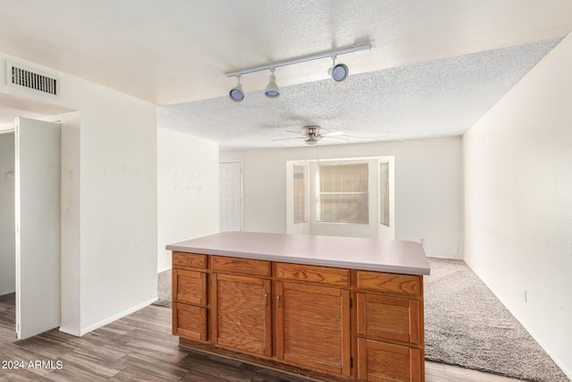 kitchen featuring brown cabinets, light countertops, visible vents, a textured ceiling, and wood finished floors