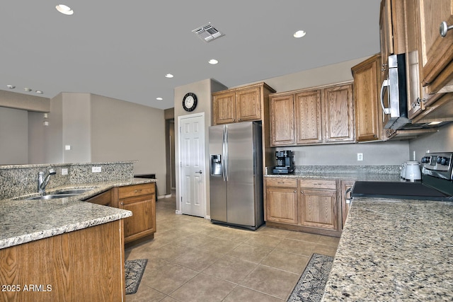 kitchen featuring light stone counters, sink, light tile patterned flooring, and appliances with stainless steel finishes