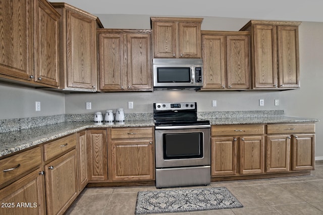 kitchen with light stone countertops, stainless steel appliances, and light tile patterned floors