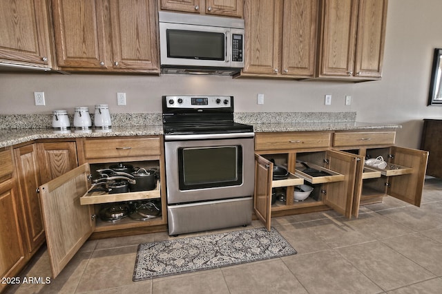 kitchen featuring light stone counters, light tile patterned floors, and stainless steel appliances