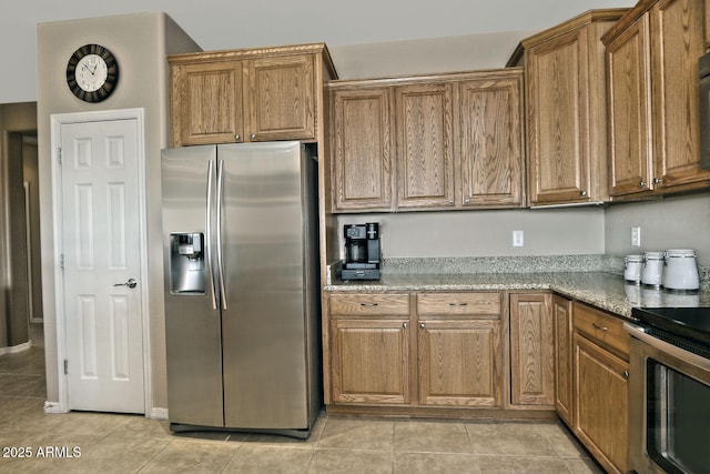 kitchen with light tile patterned floors, stainless steel appliances, and stone countertops