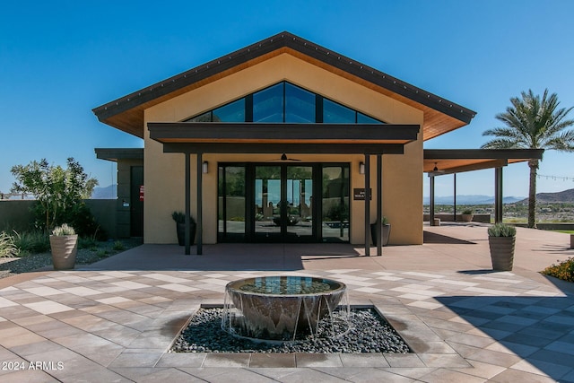 back of house with ceiling fan, a patio area, a mountain view, and french doors