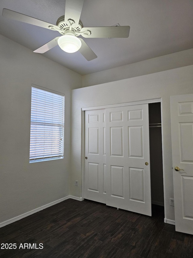 unfurnished bedroom featuring a closet, a ceiling fan, baseboards, and dark wood-style flooring